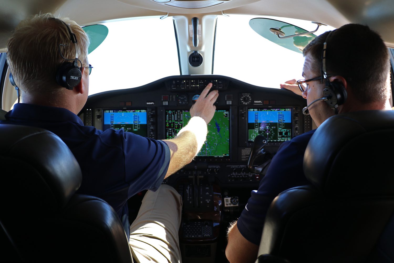 Two pilots reviewing the flight deck of a Citation Mustang in flight
