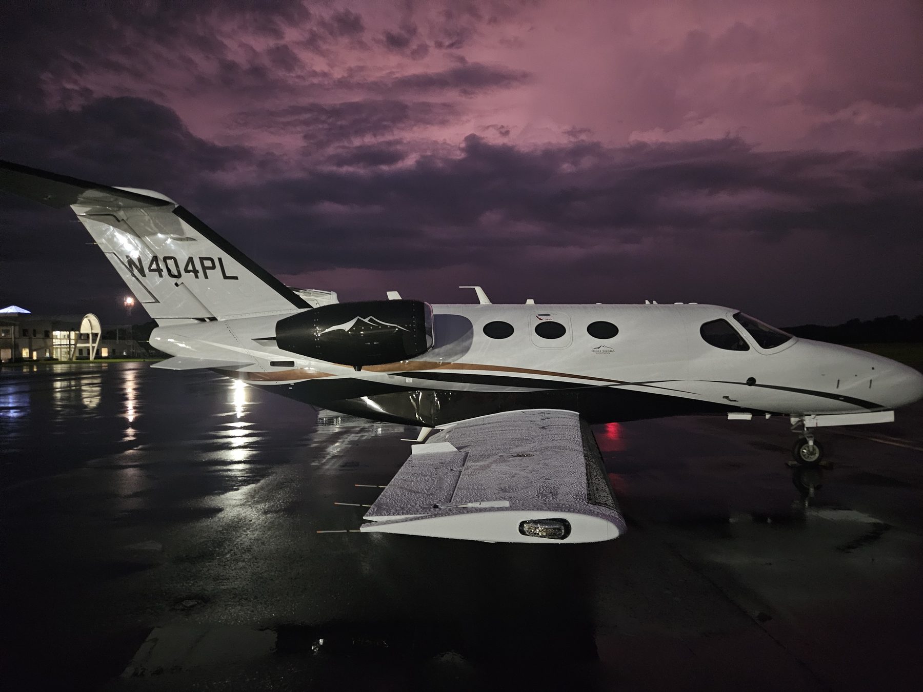 Citation Mustang on a wet ramp as a storm clears at dusk, sky glowing purple